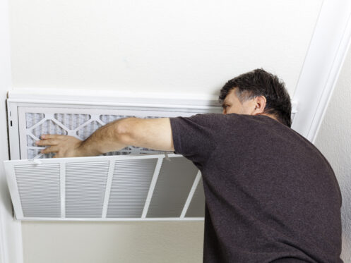 A man replacing an AC filter in Nashua, NH